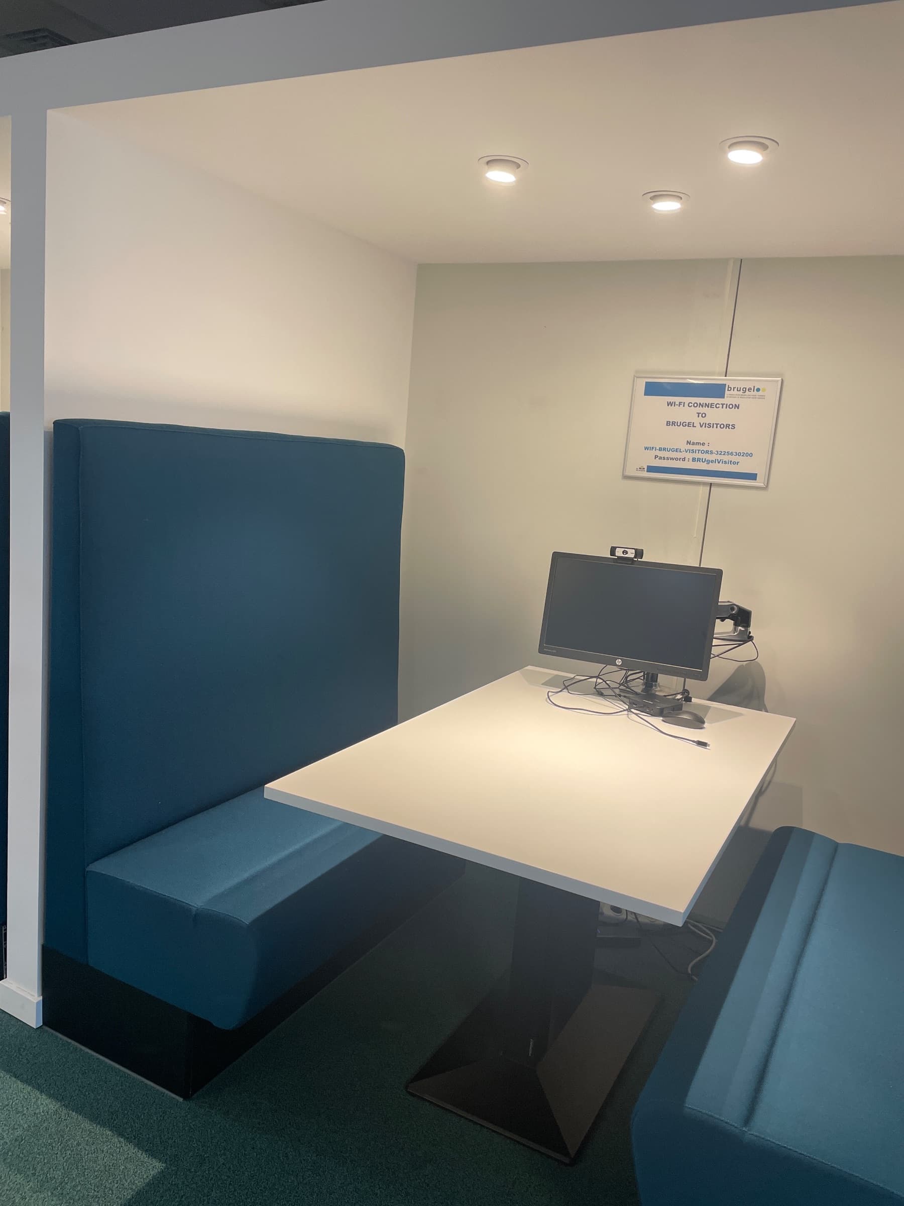 Teal stoffen vergadercabine met witte tafel en geïntegreerde technologie